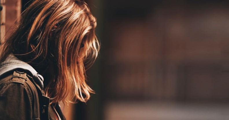 Jeune fille accotée à un mur, triste