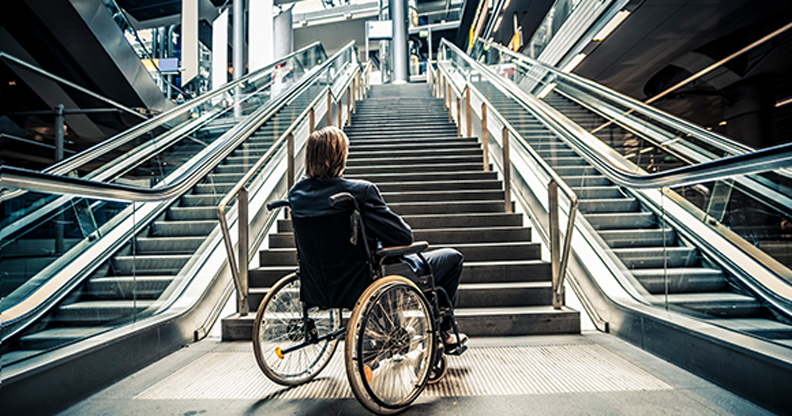 Une personne en fauteuil roulant bloquée au bas d'un grand escalier