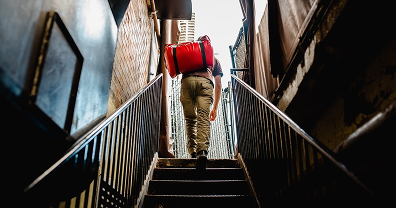 Personne qui monte les escaliers avec un sac à dos rouge