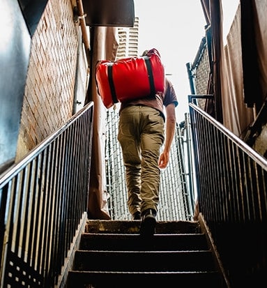 Jeune homme qui monte les escaliers avec son cas de voyage.